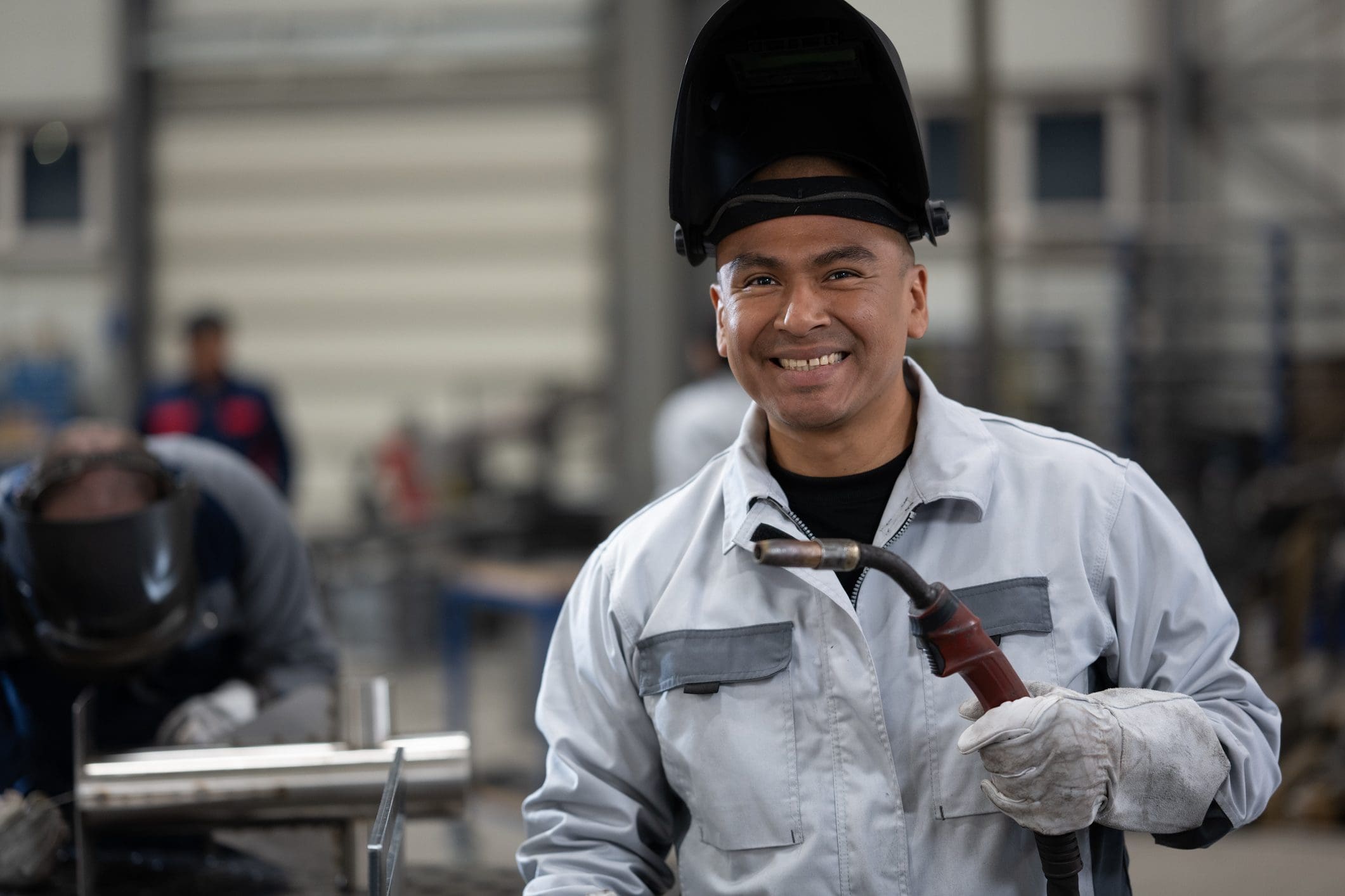 Welder standing in factory Welding - sheet metal fabrication.Portrait of smiling male welder holding welding torch in factory.